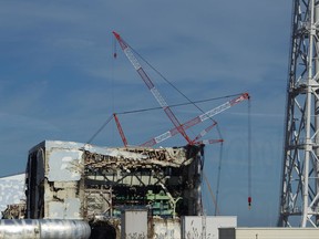 FILE - In this Nov. 12, 2011, the Unit 4 reactor building of the crippled Fukushima Dai-ichi nuclear power station is seen through a bus window in Okuma, Japan. A Japanese court has awarded compensation totaling about 500 million yen ($4.5 million) to thousands of former Fukushima residents who demanded damages for their lost livelihood due to the 2011 nuclear crisis, ordering the government to split the cost with the utility. The Fukushima District Court on Tuesday, Oct. 10, 2017,  said the government had failed to order the utility, Tokyo Electric Power Co., to improve safety measures despite knowing as early as 2002 of a risk of a massive tsunami in the region. (AP Photo/David Guttenfelder, File)