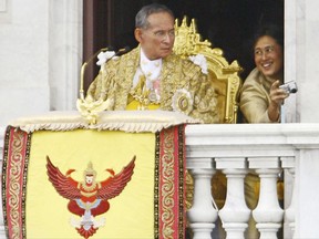 FILE - In this June 9, 2006, file photo, then Thailand's King Bhumibol Adulyadej, left, waits to address the crowd as Princess Sirindhorn takes photographs in Bangkok. Thais marked one year on Friday, Oct. 13, 2017, since the death of King Bhumibol with formal ceremonies and acts of personal devotion before an elaborate five-day funeral later this month. (AP Photo/Wasan Wanichakorn, File)