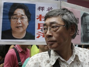 FILE - In this June 18, 2016, file photo, freed Hong Kong bookseller Lam Wing-kee stands next to a placard with a picture of missing bookseller Gui Minhai, left, in front of his book store during a march in Hong Kong. Mainland Chinese authorities released detained Hong Kong bookseller Gui and he was reunited with his relatives, one of his friends said Friday, Oct. 27, 2017. Gui, a Swedish citizen, was one of five employees of a Hong Kong bookshop specializing in salacious tales about high-level Chinese politics who were believed to have been abducted and spirited to the mainland two years ago. (AP Photo/Kin Cheung, File)