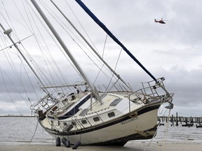 A U.S. Coast Guard helicopter flies over a beached sail boat near Margaritaville and the Golden Nugget in Biloxi, Miss., Sunday, Oct. 8, 2017, after Hurricane Nate made landfall on the Gulf Coast.