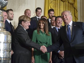President Donald Trump, right, shakes hands with Pittsburgh Penguins owner Ronald Burkle, third from left, as first lady Melania Trump, center in green, watches, with Mario Lemieux during a ceremony to honour the 2017 NHL Stanley Cup Champion Pittsburgh Penguins, Tuesday, Oct. 10, 2017, in the East Room of the White House in Washington.