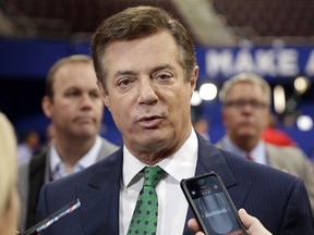 Then Trump campaign chairman Paul Manafort talks to reporters on the floor of the Republican National Convention in Cleveland on July 17, 2016, as Rick Gates listens at back left.