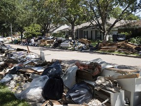 FILE - In this Sept. 7, 2017 file photo, flood damaged debris from homes lines the street in the aftermath of Hurricane Harvey in Houston. One month after Harvey dumped record rainfall in the Houston area, many neighborhoods and suburbs of the nation's fourth largest city continue cleaning up after the storm. While the larger shelters have closed and much of the city has gone back to normal, huge piles of debris still line streets in numerous neighborhoods as many residents try to salvage their homes. (AP Photo/Matt Rourke, File)