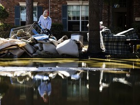 FILE - In this Sept. 7, 2017, file photo, homeowner Sohail Soomro dumps flood damage debris on his front yard in the aftermath of Hurricane Harvey at the Canyon Gate community in Katy, Texas. Health officials in Texas will be on watch in coming weeks for any increases in mosquito-borne diseases including West Nile virus and Zika after Harvey's heavy rains and flooding brought water that filled ponds and ditches and crept into trash and debris that piled up.(AP Photo/Matt Rourke, File)