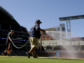 Grounds crew members wet the infield at Minute Maid Park as preparations continue for Game 3 of baseball's World Series, Thursday, Oct. 26, 2017, in Houston. The Houston Astros will play the Los Angeles Dodgers, Friday. (AP Photo/Charlie Riedel)