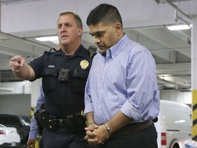 Wesley Mathews is escorted by police during his transfer to Dallas County jail in Dallas, Wednesday, Oct. 25, 2017.  Mathews, the father of  3-year-old Sherin Mathew, a missing toddler whose body was found in a culvert under a road in suburban Dallas, has changed his story to say the girl didn't wander off two weeks ago, but that she choked to death while drinking milk in the family's garage.  Police on Monday charged Mathews with first-degree felony injury to a child. (AP Photo/LM Otero)
