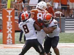 Oklahoma State defenders Rodarius Williams (8) and Chad Whitener (45) knock the ball loose from Texas tight end Cade Brewer (80) during the second half of an NCAA college football game, Saturday, Oct. 21, 2017, in Austin, Texas. Oklahoma State won 13-10 in overtime. (AP Photo/Michael Thomas)