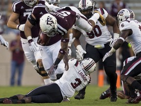Texas A&M running back Trayveon Williams (5) is knocked off his feet by South Carolina defensive back Chris Lammons (3) during the first quarter of an NCAA college football game Saturday, Sept. 30, 2017, in College Station, Texas. (AP Photo/Sam Craft)