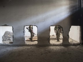 In this Oct. 20, 2017, photo, nembers of the U.S.-backed Syrian Democratic Forces (SDF) walk inside the stadium that was the site of Islamic State fighters' last stand in the city of Raqqa, Syria.