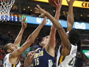 Denver Nuggets center Nikola Jokic (15) shoots as Utah Jazz's Rudy Gobert, left, and Donovan Mitchell, right, defend during the first half of an NBA basketball game Wednesday, Oct. 18, 2017, in Salt Lake City. (AP Photo/Rick Bowmer)