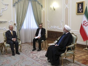 In this photo released by the office of the Iranian Presidency, President Hassan Rouhani, right, speaks with Director General of the International Atomic Energy Agency, IAEA, Yukiya Amano, left, during their meeting, in Tehran, Iran, Sunday, Oct. 29, 2017. An unidentified interpreter sits at center. (Iranian Presidency Office via AP)