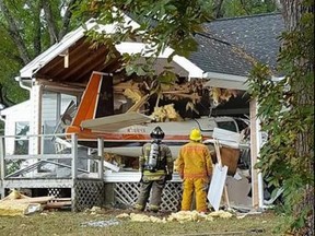 In this photo provided by Christopher Shirk, firefighters inspect the wreckage of a small plane after it collided into a house in Middlesex, Va., on Saturday, Oct. 7, 2017. Officials said the three people on board survived with minor injuries, and no one was home at the time of the crash. (Christopher Shirk via AP)