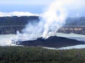 This Sunday, Oct. 1, 2017 photo provided by GeoHazards Divison, Vanuatu Meteorological and GeoHazards Department, shows an aerial view of the volcanic cone that has formed in Lake Vui near the summit of Ambae Island, Vanuatu. The evacuation of the Vanuatu island was continuing on Monday, Oct. 2, 2017 even after scientists said an erupting volcano had stabilized. A makeshift fleet of vessels ranging from large landing craft to tiny water taxis was moving thousands of people from Ambae island to other nearby islands in the Pacific archipelago. (Brad Scott/GeoHazards Divison, VMGD via AP)