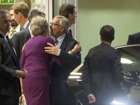 European Commission President Jean-Claude Juncker, center right, embraces British Prime Minister Theresa May, center left, after a meeting at EU headquarters in Brussels on Monday, Oct. 16, 2017. EU officials said that a meeting between British Prime Minister Theresa May and EU officials on Monday evening would span much more than the struggling Brexit talks to include current trade relations with global partners. (AP Photo/Virginia Mayo)