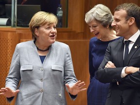 German Chancellor Angela Merkel, left, speaks with British Prime Minister Theresa May, center, and French President Emmanuel Macron prior to a round table meeting at an EU summit in Brussels on Thursday, Oct. 19, 2017. British Prime Minister Theresa May headed to a European Union summit Thursday with a pledge to treat EU residents well once Britain leaves the bloc. (AP Photo/Geert Vanden Wijngaert)