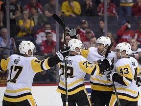 Pittsburgh Penguins defenseman Kris Letang (58) celebrates his goal with Conor Sheary (43), Patric Hornqvist (72) and Bryan Rust (17) during the first period of an NHL hockey game against the Washington Capitals, Wednesday, Oct. 11, 2017, in Washington. (AP Photo/Nick Wass)