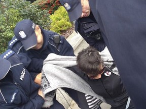 This file photo from Sept.24 2017 shows women's rights activist Klementyna Suchanow being removed from a protest by police in Warsaw. Suchanow is one case cited by Amnesty International in a new report alleging that Poland's authorities have used surveillance, prosecutions and harassment, and even excessive force in rare cases, against peaceful anti-government protesters since 2016. (AP Photo/Iwona Wyszogrodzka)