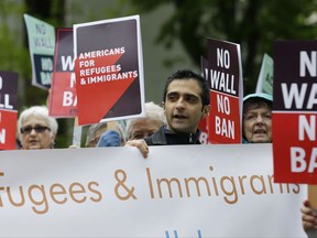 FILE--In this May 15, 2017, file photo, protesters hold signs during a demonstration against President Donald Trump's revised travel ban, Monday, May 15, 2017, outside a federal courthouse in Seattle.  Trump's six-month worldwide ban on refugees entering the United States is ending as his administration prepares to unveil new screening procedures. A State Department official says the suspension of processing for refugees ended Tuesday, the date set in Trump's executive order.  (AP Photo/Ted S. Warren, file)