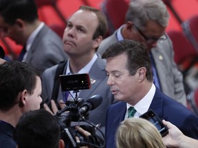 FILE - In this July 17, 2016 file photo, President Donald Trump's Campaign Chairman Paul Manafort is surrounded by reporters on the floor of the Republican National Convention in Cleveland. Rick Gates, a former business associate to Manafort and former campaign aide to Republican presidential candidate Donald Trump, is center rear.   (AP Photo/J. Scott Applewhite)