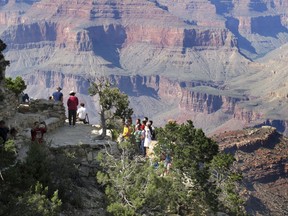 FILE - In this Aug. 19, 2015, file photo, visitors gather at an outlook on the South Rim of Grand Canyon National Park in northern Arizona. Democratic senators are harshly criticizing a National Park Service plan to impose steep increases in entrance fees at 17 of its most popular parks, including the Grand Canyon, Yosemite, Yellowstone and Zion. (AP Photo/Felicia Fonseca, File)