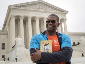 In this Oct. 13, 2017, photo, Bryant Johnson, personal trainer for Supreme Court Justice Ruth Bader Ginsburg poses in Washington, with his new book, "The RBG Workout: How She Stays Strong ... and You Can Too!" Besides the 84-year-old Ginsberg, Johnson, who now also trains Justice Stephen Breyer and Justice Elena Kagan. Johnson says he hopes the book will help convince people: "You're never too old to do something."  (AP Photo/J. Scott Applewhite)