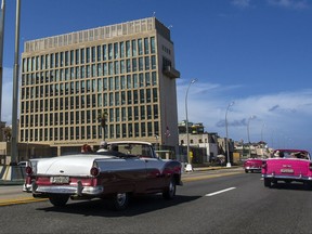 In this Oct. 3, 2017 photo, tourists ride classic convertible cars on the Malecon beside the United States Embassy in Havana, Cuba. Less than three years have passed since the longtime enemies began an ambitious diplomatic experiment, restoring formal ties despite lingering resentments and potent political opposition on both sides of the Florida Straits. Despite all that, a delicate detente took hold in 2015 and has slowly but steadily progressed. And now the experiment was upended when American embassy workers started falling ill last year in Havana, the unwitting victims of eerie, invisible attack.(AP Photo/Desmond Boylan)
