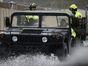 FILE - In this Sept. 20, 2017 file photo, rescue personnel drive on a road flooded by the heavy rains brought on by Hurricane Maria, in Humacao, Puerto Rico. The storm swept across the island causing at least 48 deaths, according to the official tally. It caused widespread flooding and knocked out the entire power grid for the island of 3.4 million people. (AP Photo/Carlos Giusti, File)