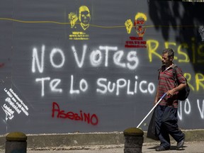 A man pass by a mural that in Spanish reads "Not vote, I beg you" in a street of Caracas, Venezuela, Saturday, Oct 14, 2017. Venezuelans head to the ballot box Sunday in regional elections that could tilt a majority of the states' 23 governorships back into opposition control for the first time in nearly two decades of socialist party rule.  (AP Photo/Ariana Cubillos)