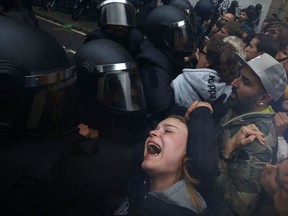 FILE -  This is a Sunday,  Oct. 1,  2017 file photo of a  girl as he  grimaces as Spanish National Police pushes away Pro-referendum supporters outside the Ramon Llull school assigned to be a polling station by the Catalan government in Barcelona, Spain. For local teacher Elisa Aroca, Sunday will go down as the day when Spain lost the battle for the hearts and minds of Catalonia. (AP Photo/Emilio Morenatti/File)