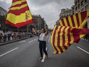 A woman waves flags of Catalonia and Spain as people celebrate a holiday known as "Dia de la Hispanidad" or Spain's National Day in Barcelona, Spain, Thursday, Oct. 12, 2017. Spain's celebrates its national day amid one of the country's biggest crises ever as its powerful northeastern region of Catalonia threatens independence. (AP Photo/Santi Palacios)
