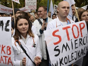 Young doctors rally in front of the prime minister's office to demand increases of their low earnings and more spending on the chronically strapped and inefficient health care, in Warsaw, Poland, Saturday, Oct. 14, 2017. The placard right reads: Stop dying in queues. (AP Photo/Alik Keplicz)