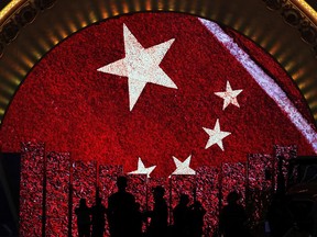 Visitors is silhouetted as they watch a video display boards showing the Chinese flag at an exhibition highlighting China's achievements under five years of leadership by Chinese President Xi Jinping at the Beijing Exhibition Hall in the capital city where the 19th Party Congress is held in Beijing, Monday, Oct. 23. (AP Photo/Andy Wong)