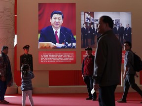 In this Oct. 23, 2017 photo, a child takes a photo of a man posing with a picture of Chinese President Xi Jinping at an exhibition highlighting China's achievements under five years of his leadership at the Beijing Exhibition Hall in the capital city where the 19th Party Congress is held. The exhibition coincides with the twice-a-decade national congress, and the two events, one teeming with ordinary citizens, the other under tight security, show how Xi has centralized power and is leading China into a confident, gleaming new era. It's an approach to governing that seems to have strong resonance with China's public. (AP Photo/Andy Wong)