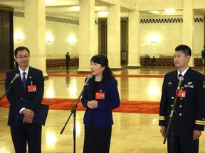 Communist Party delegates stand in front of microphones as they participate in a group interview with the media on the sidelines of China's 19th Party Congress at the Great Hall of the People in Beijing, Thursday, Oct. 19, 2017. China's ruling Communist Party has been touting a new "Party Delegates' Corridor" as a rare opportunity for reporters to spontaneously raise questions to cadres and officials on the sidelines of a major congress as they pass by at the Great Hall of the People. But the stagecraft that goes into it becomes evident as soon as the speakers are rolled out one by one. (AP Photo/Gerry Shih)