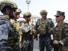 Philippine Navy Capt. Roy Vincent Trinidad, right, talks to Australian Navy officers shortly upon disembarking from the Royal Australian Navy HMAS Adelaide, an amphibious assault ship and landing helicopter dock, docked in the South Harbor for a five-day port call, Tuesday, Oct. 10, 2017, in Manila, Philippines. The visit of the HMAS Adelaide, along with another Australian Navy ship, the HMAS Darwin, a guided missile frigate, is aimed at strengthening relations between the two navies as well as provide maritime security and stability in the region. (AP Photo/Bullit Marquez)