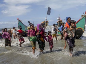 FILE - In this Sept. 14, 2017 file photo, Rohingya Muslims walk towards shore after arriving on a boat from Myanmar to Bangladesh in Shah Porir Dwip, Bangladesh. The country was caught unprepared when some 500,000 began pouring across the border in late August to escape attacks by Myanmar soldiers and Buddhist mobs, a crisis the United Nations has described as "textbook ethnic cleansing."  Some in the low-lying delta nation are worried that the staggering influx of people, if allowed to stay, could push the country's resources and economy to the brink. (AP Photo/Dar Yasin, File)