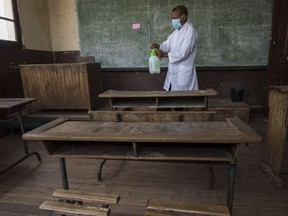 In this photo taken Tuesday Oct. 10, 2017, a member of staff at a school in Antananarivo sprays against plague in a classroom at a school in the capital Antananarivo, Madagascar, as schools remain shut due the outbreak. A plague outbreak has brought panic to the city dwellers with schools closed and public gatherings banned as the death toll still mounts in the Indian Ocean island nation. (AP Photo/Alexander Joe)