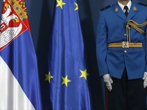 In this photo taken Monday, Oct. 2, 2017, a member of the Serbian Honor guard stands by European Union flag and Serbian flag, left, during a press conference at the Serbia Palace, in Belgrade, Serbia. The EU has warned European member candidate Serbia that appointing retired Gen. Vladimir Lazarevic as a lecturer at the country's military academy goes against EU's principles, as Lazarevic was sentenced by a U.N. war crimes tribunal for atrocities committed by Serb troops in Kosovo during the 1998-99 war. (AP Photo/Darko Vojinovic)