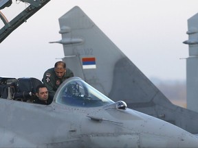 In this photo taken Tuesday, Oct. 17, 2017, Serbian Defense Minister Aleksandar Vulin, left, inspects an Mig 29 fighter jet at the military airport Batajnica, near Belgrade, Serbia. Vulin told Serbia's state TV on Thursday Oct. 19, 2017 that  Gen. Vladimir Lazarevic, a former general convicted for war crimes and other Serb commanders who took part in a bloody crackdown against Kosovo's Albanians in the 1990s, will be invited to teach at the Balkan country's military academy. (AP Photo/Darko Vojinovic)