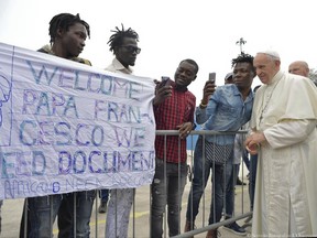 Pope Francis poses for selfies with migrants as they display a banner asking for a legal status, at a regional migrant center, in Bologna, Italy, Sunday, Oct. 1, 2017. Pope Francis is in Cesena and Bologna for a one-day visit. (L'Osservatore Romano/ Pool photo via AP)