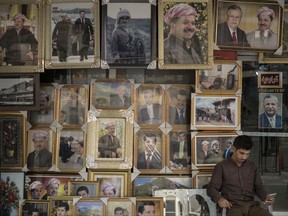 A man sits outside a store selling photos of Kurdish President Masoud Barzani and members of his family, in central Irbil, Iraq, Sunday, Oct. 29, 2017. A Kurdish official said Sunday that Barzani, has informed parliament that he'll not stay in office as his term expires Nov. 1 in the wake of a controversial vote on independence from Iraq. (AP Photo/Felipe Dana)