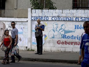 In this Oct. 18, 2017 photo, commuters wait for a public bus in Guarenas, Venezuela. Designed as a bedroom community for working- and middle-class families, the city is known as the origin of violent 1989 protests known as the "Caracazo," which spilled into the capital, left more than 300 people dead and destabilized the government. (AP Photo/Fernando Llano)