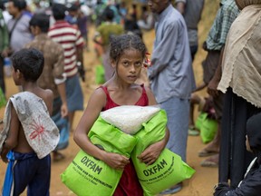 Newly arrived Rohingya girl carries food rations in Kutupalong, Bangladesh, Saturday, Sept. 30, 2017. Five weeks after the mass exodus of Rohingya from Myanmar began, the U.N. says the total number of arrivals in Bangladesh has now topped 501,000, and refugees are still arriving. (AP Photo/Gemunu Amarasinghe)