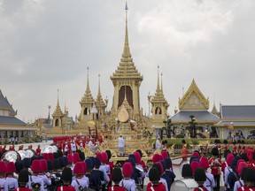 The ceremonial urn of Thailand's late King Bhumibol Adulyadej arrives at the crematorium during the funeral procession as royal crematorium is seen in the background in Bangkok, Thailand, Thursday, Oct. 26, 2017. Tearful Thais clad in black mourned on Bangkok's streets or at viewing areas around the nation Thursday as elaborate funeral ceremonies steeped in centuries of royal tradition were held for King Bhumibol Adulyadej following a year of mourning. (AP Photo/Wason Wanichakorn)