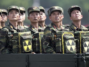 FILE - In this July 27, 2013, file photo, North Korean soldiers carrying packs marked with the nuclear symbol turn and look towards leader Kim Jong Un during a military parade in Pyongyang, North Korea. Securing North Korea's missile launchers and nuclear, chemical and biological weapons sites would likely be a chief priority for China in the event of a major crisis involving its communist neighbor, analysts say, although Beijing so far is keeping mum on any plans. (AP Photo/Wong Maye-E, File)