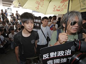 Former student leader Lester Shum, left, arrives at the High Court to hear the verdict in a case of contempt against him and other activists in Hong Kong, Friday, Oct. 13, 2017. The court has convicted 20 activists, including Shum and leader Joshua Wong, for defying authorities trying to clear a protest site during massive 2014 pro-democracy demonstrations in the Chinese-controlled city. The Chinese words on placard read "Against political prosecution, Rimsky Yuen Kwok-keung step down." (AP Photo/Kin Cheung)