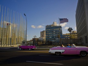 FILE - In this Jan. 12, 2017 file photo, tourists ride in classic American convertible cars past the United States embassy, right, in Havana, Cuba. Cuba on Oct. 26 presented its most detailed defense to date against U.S. accusations that American diplomats in Havana were subjected to mysterious sonic attacks that left them with a variety of ailments including headaches, hearing problems and concussions. (AP Photo/Ramon Espinosa, File)