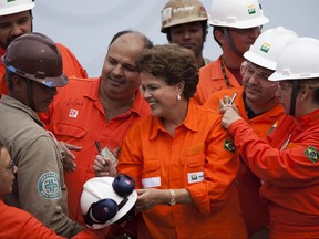 FILE - In this June 3, 2011 file photo, Brazil's President Dilma Rousseff autographs a worker's hard hat during the opening ceremony of the Petrobras P-56 oil platform in Angra dos Reis, Brazil. A Brazilian court has ordered the ex-President's assets frozen in connection with an estimated $580 million loss at state oil company Petrobras resulting from the purchase of an oil refinery in Pasadena, Texas. (AP Photo/Felipe Dana, File)