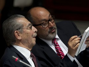 FILE - In this March 19, 2013 photo, Guatemala's former dictator Jose Efrain Rios Montt, left, talks with his lawyer Moises Galindo during his trial on genocide charges in Guatemala City. Galindo  has been arrested Thursday, Oct. 5 2017, for alleged ties to money laundering. National Civil Police spokesman Pablo Castillo says that Moises Galindo was arrested on a judge's order. (AP Photo/Moises Castillo, File)
