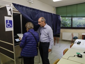 A president of a voting section explains the electronic voting system to Giuseppina Guatri an elderly citizen at a polling station in Milan, Italy, Sunday, Oct.22, 2017. Voters in the wealthy northern Italian regions of Lombardy and Veneto are heading to the polls to decide if they want to seek greater autonomy from Rome, riding a tide of self-determination that is sweeping global politics. (AP Photo/Luca Bruno)